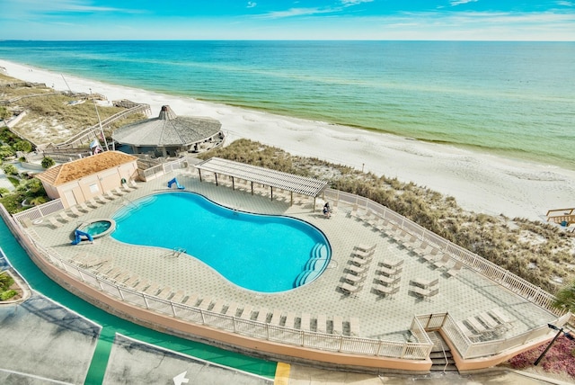 view of swimming pool featuring a patio area, a water view, and a view of the beach