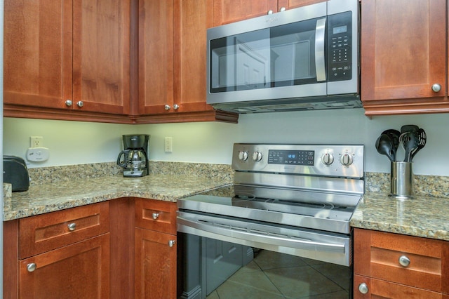 kitchen with appliances with stainless steel finishes, tile flooring, and light stone counters