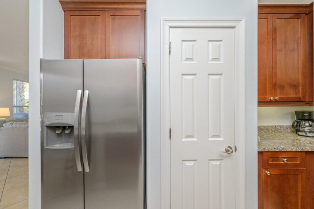 kitchen featuring stainless steel refrigerator with ice dispenser, light tile flooring, and light stone counters