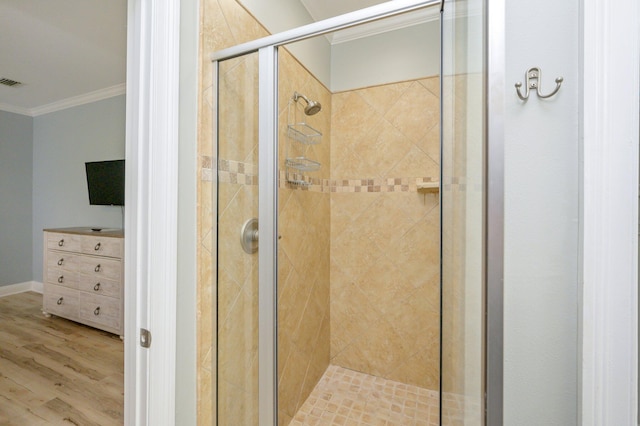 bathroom featuring ornamental molding, a shower with door, and hardwood / wood-style floors