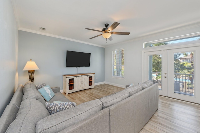 living room with ornamental molding, light hardwood / wood-style floors, ceiling fan, and french doors