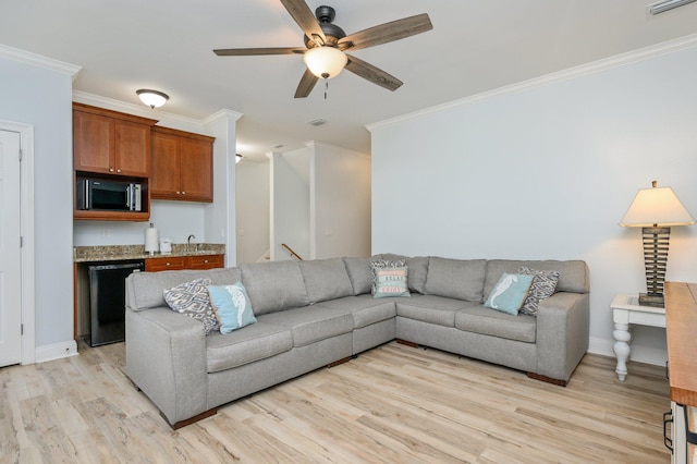 living room with crown molding, light hardwood / wood-style flooring, ceiling fan, and sink