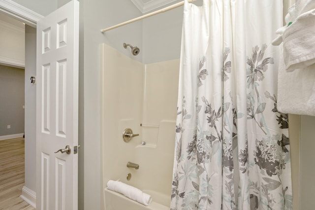 bathroom with wood-type flooring, crown molding, and shower / bath combo with shower curtain