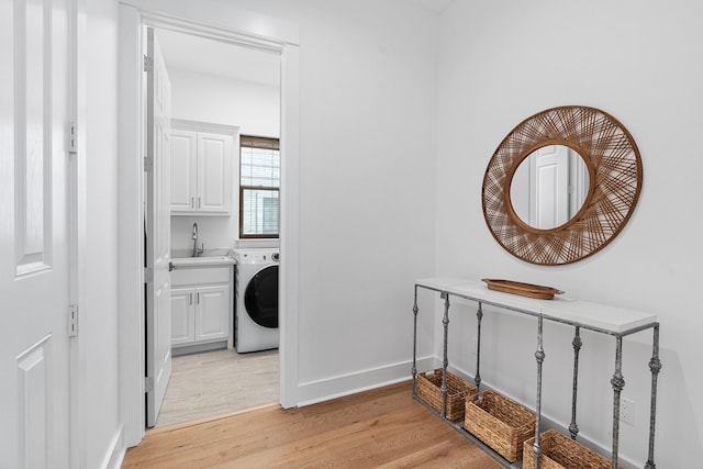 hallway featuring sink, light hardwood / wood-style floors, and washer / dryer