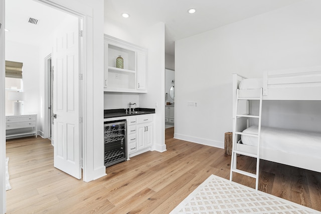 kitchen featuring wine cooler, sink, light hardwood / wood-style flooring, and white cabinetry