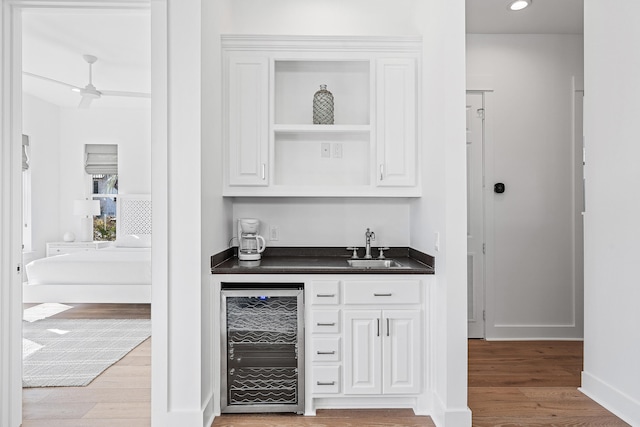 bar featuring sink, wine cooler, white cabinets, and hardwood / wood-style floors