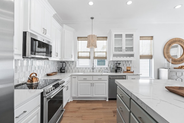 kitchen with appliances with stainless steel finishes, tasteful backsplash, white cabinetry, sink, and pendant lighting