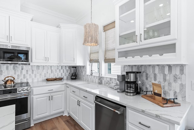 kitchen with appliances with stainless steel finishes, white cabinets, tasteful backsplash, dark wood-type flooring, and hanging light fixtures