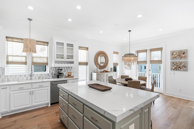 kitchen with decorative light fixtures, backsplash, white cabinetry, a center island, and stainless steel dishwasher