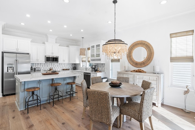 dining area featuring ornamental molding, light hardwood / wood-style flooring, and an inviting chandelier