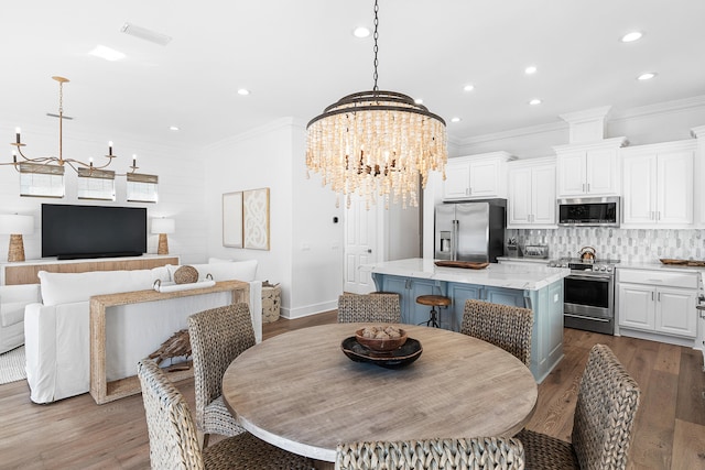 dining room with crown molding, hardwood / wood-style flooring, and an inviting chandelier