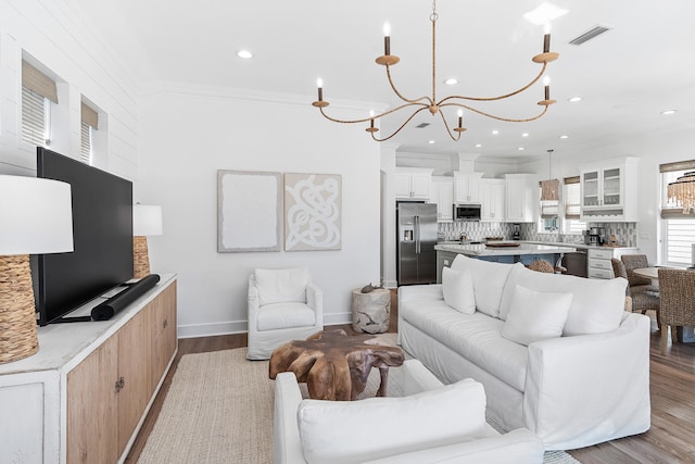 living room featuring hardwood / wood-style floors, a notable chandelier, and crown molding