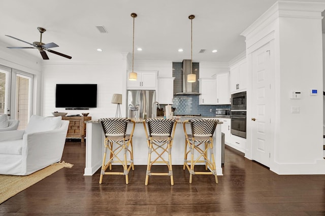 kitchen featuring appliances with stainless steel finishes, a breakfast bar, hanging light fixtures, and wall chimney range hood