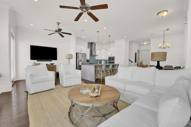 living room with ceiling fan with notable chandelier, wood-type flooring, and ornamental molding