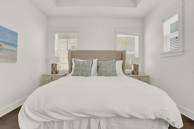 bedroom featuring dark hardwood / wood-style floors and a tray ceiling