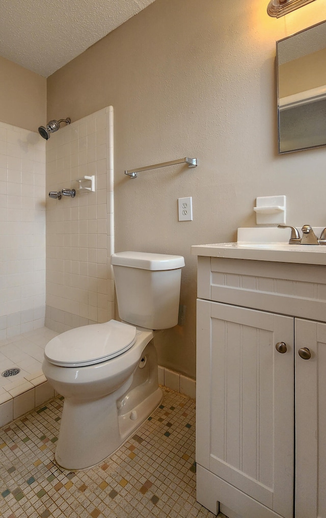 bathroom featuring vanity, tile patterned floors, toilet, a textured ceiling, and a tile shower