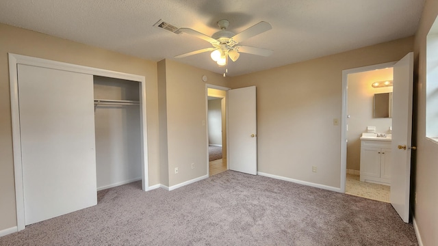 unfurnished bedroom with a textured ceiling, ceiling fan, light carpet, and a closet