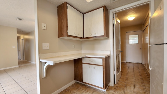 kitchen with a textured ceiling and stainless steel refrigerator