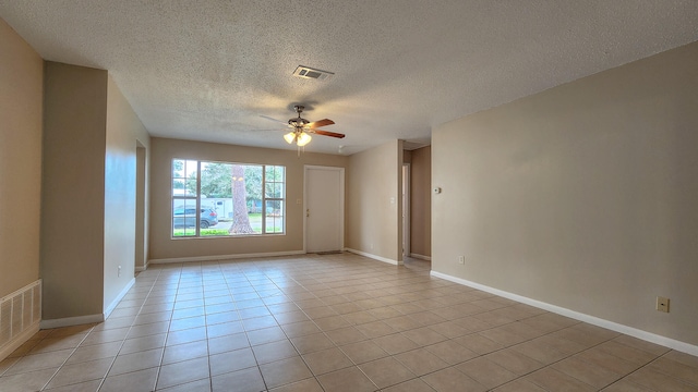 empty room featuring ceiling fan, light tile patterned floors, and a textured ceiling