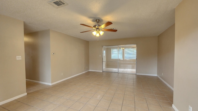 tiled empty room with ceiling fan and a textured ceiling