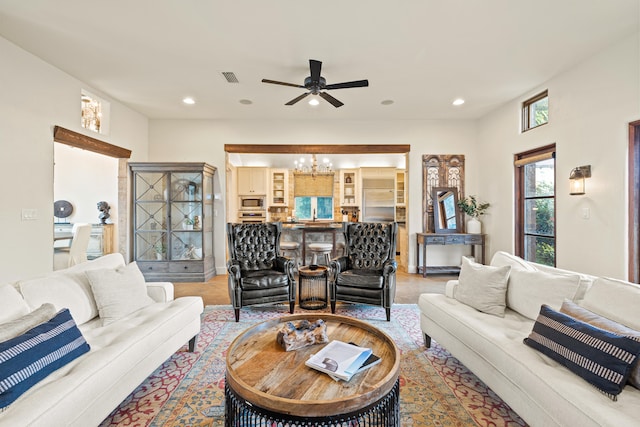 living room featuring ceiling fan with notable chandelier and light hardwood / wood-style floors