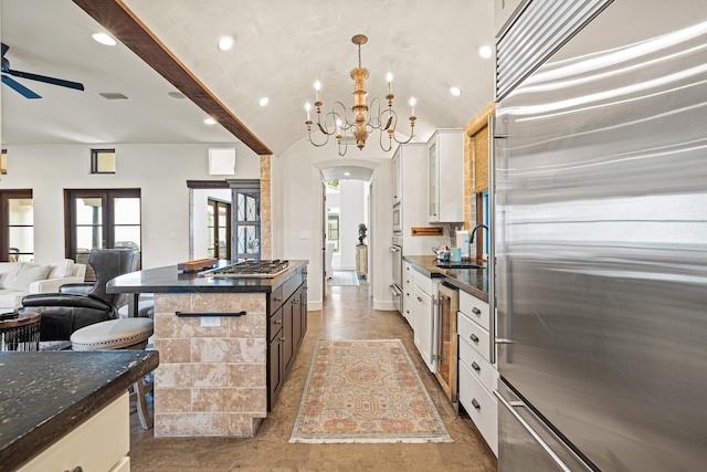 kitchen featuring decorative light fixtures, beamed ceiling, white cabinets, ceiling fan with notable chandelier, and appliances with stainless steel finishes