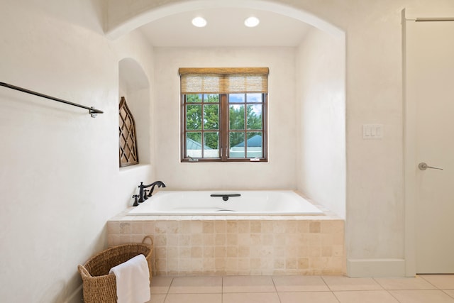 bathroom with tile flooring and tiled bath