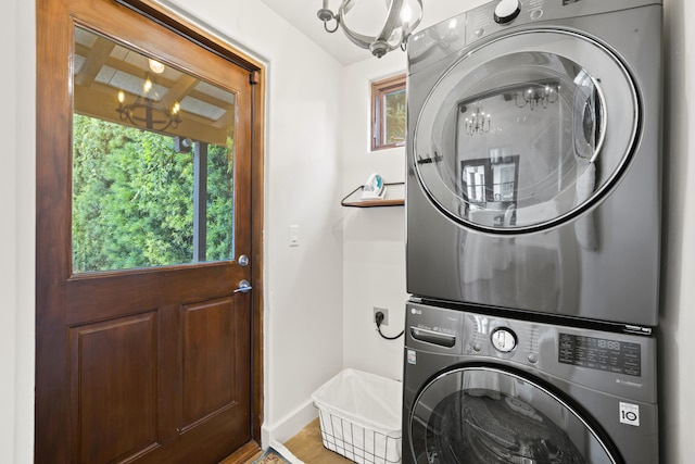 clothes washing area with an inviting chandelier and stacked washer / dryer