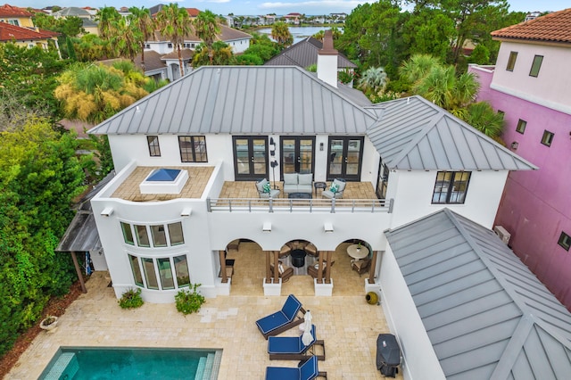 rear view of house with french doors, an outdoor living space, and a patio area