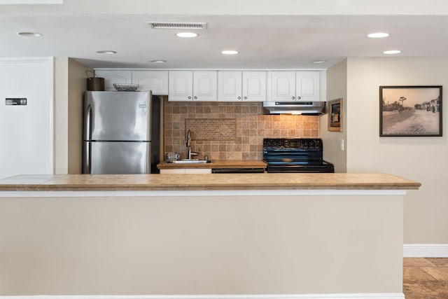 kitchen with light tile floors, range, tasteful backsplash, white cabinetry, and stainless steel fridge