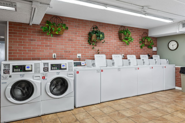 washroom featuring brick wall, separate washer and dryer, and light tile flooring