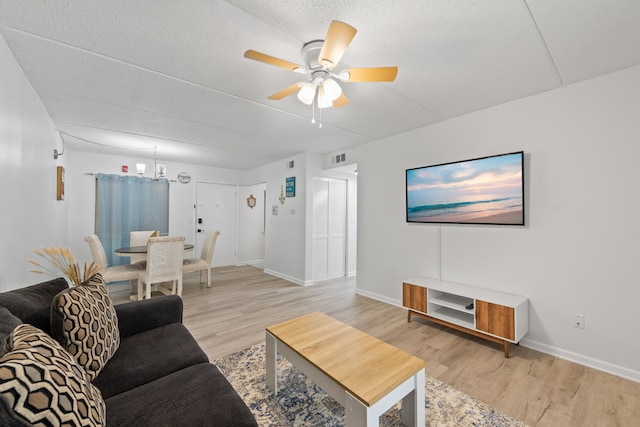 living room featuring hardwood / wood-style flooring, ceiling fan, and a textured ceiling