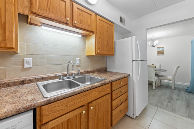 kitchen featuring sink, an inviting chandelier, white appliances, and light tile floors