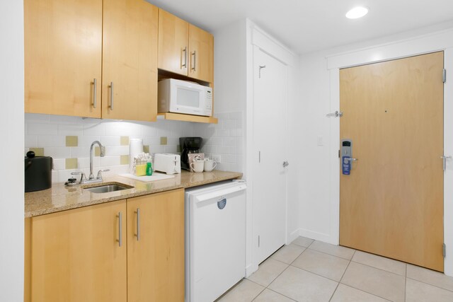 kitchen with sink, light tile patterned floors, white appliances, light stone countertops, and backsplash