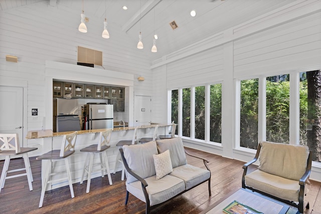 interior space with dark wood-type flooring, high vaulted ceiling, and wood walls