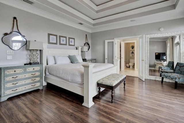 bedroom featuring ensuite bath, dark wood-type flooring, a tray ceiling, and ornamental molding