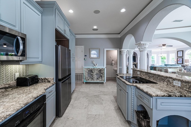 kitchen with ornate columns, ceiling fan, stainless steel appliances, dark stone countertops, and ornamental molding