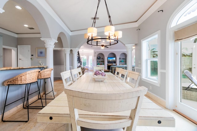 dining area with a healthy amount of sunlight, ornamental molding, and decorative columns