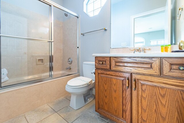 full bathroom featuring toilet, bath / shower combo with glass door, tile patterned floors, and vanity