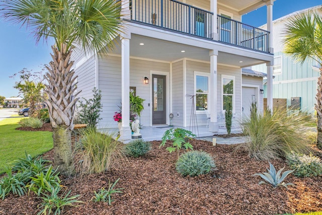 view of exterior entry featuring a balcony and covered porch