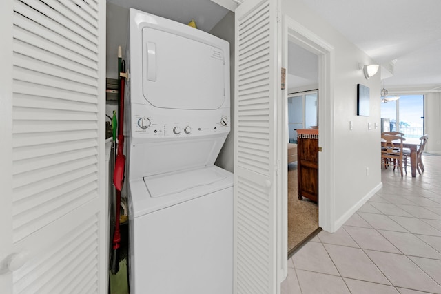 laundry area with stacked washer / dryer and light tile floors