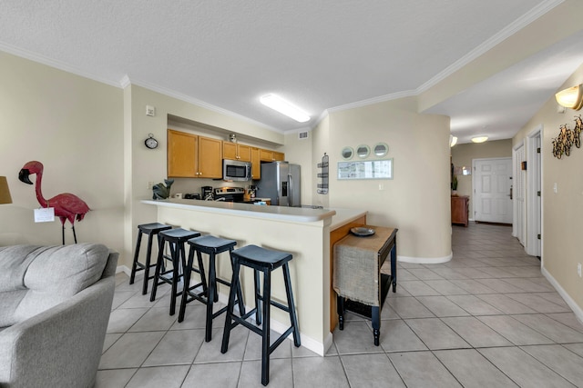 kitchen featuring crown molding, stainless steel appliances, kitchen peninsula, and light tile flooring