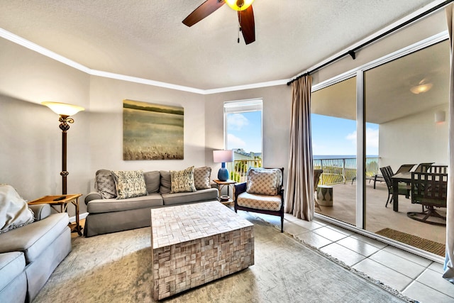 tiled living room with a water view, a textured ceiling, ceiling fan, and crown molding