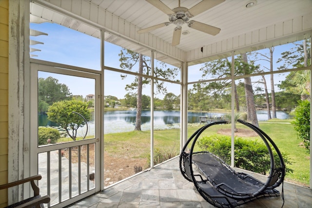 sunroom with ceiling fan and a water view