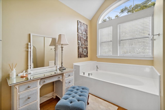 bathroom with hardwood / wood-style floors, a bathing tub, vanity, and vaulted ceiling