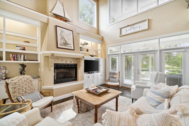 living room with built in features, french doors, a towering ceiling, and a premium fireplace