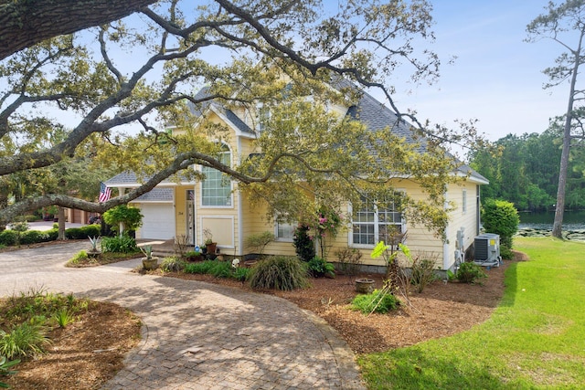 view of front of house with central AC, a front lawn, and a garage