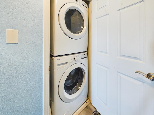 laundry area with stacked washer and clothes dryer and hardwood / wood-style flooring