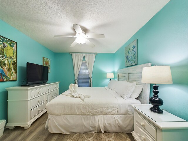 bedroom featuring dark hardwood / wood-style floors, ceiling fan, and a textured ceiling