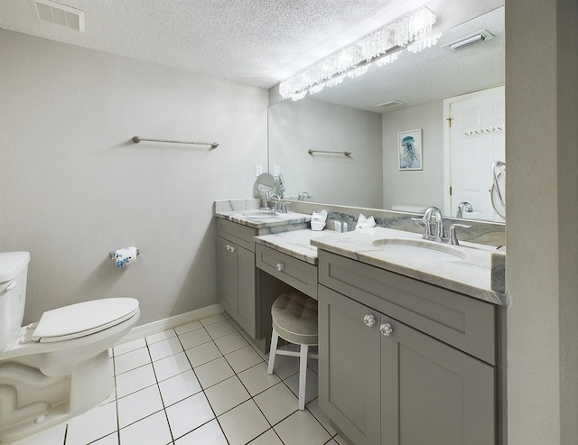 bathroom with tile patterned floors, vanity, a textured ceiling, and toilet